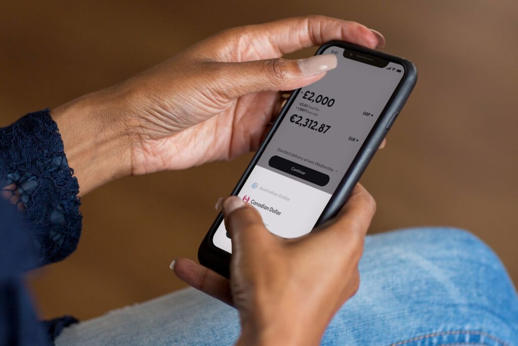 Hands holding a smartphone using a banking app to transfer money.